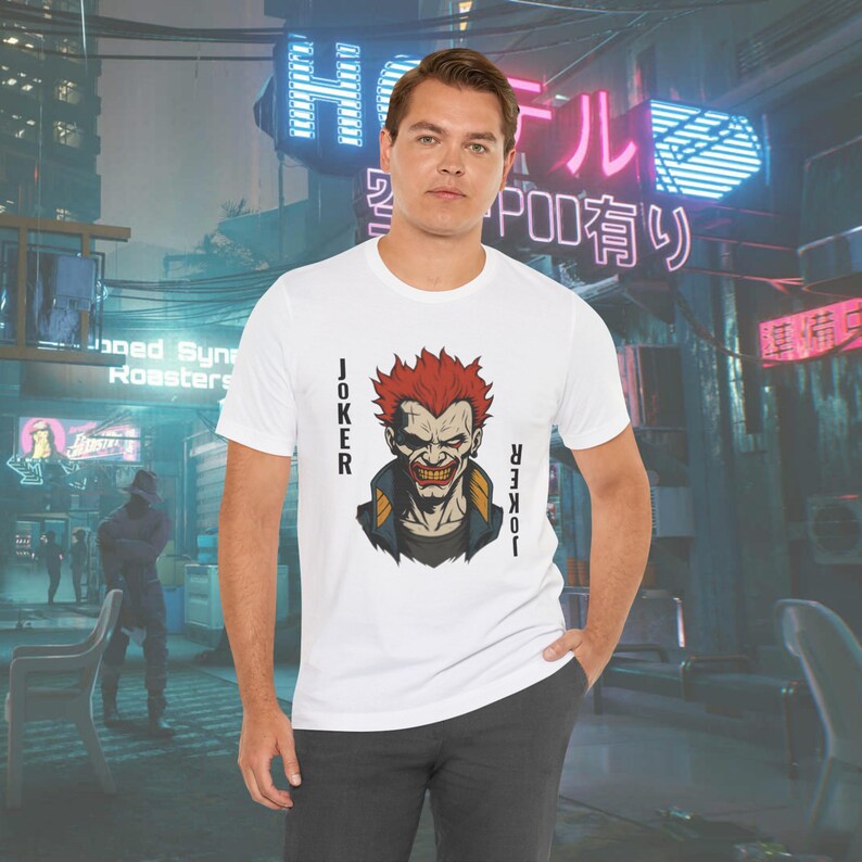 Peut inclure: T-shirt blanc avec un motif du personnage du Joker, aux cheveux roux et au sourire sinistre. Le mot "JOKER" est imprim&eacute; verticalement de chaque c&ocirc;t&eacute; du motif. Col rond.
