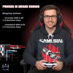 Op de afbeelding: Een marineblauwe hoodie met het woord "SAMURAI" in witte blokletters. Daaronder een rood vlammenontwerp met een robotische handafbeelding. De afbeelding bevat ook de tekst "PRINTED IN UNITED STATES". De persoon draagt een headset en een bril.