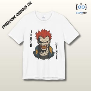 Peut inclure: T-shirt blanc avec une illustration stylis&eacute;e du Joker aux cheveux rouges et un sourire sinistre. Le mot "JOKER" est imprim&eacute; verticalement des deux c&ocirc;t&eacute;s de l'image. Le t-shirt est intitul&eacute; "CYBERPUNK-INSPIRED TEE".