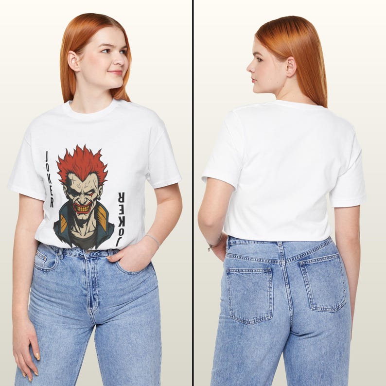 Peut inclure: T-shirt blanc avec un graphisme du Joker aux cheveux roux et le mot "JOKER" imprim&eacute; verticalement des deux c&ocirc;t&eacute;s. Le t-shirt est port&eacute; avec un jean en denim bleu clair. Le dos du t-shirt est blanc uni.