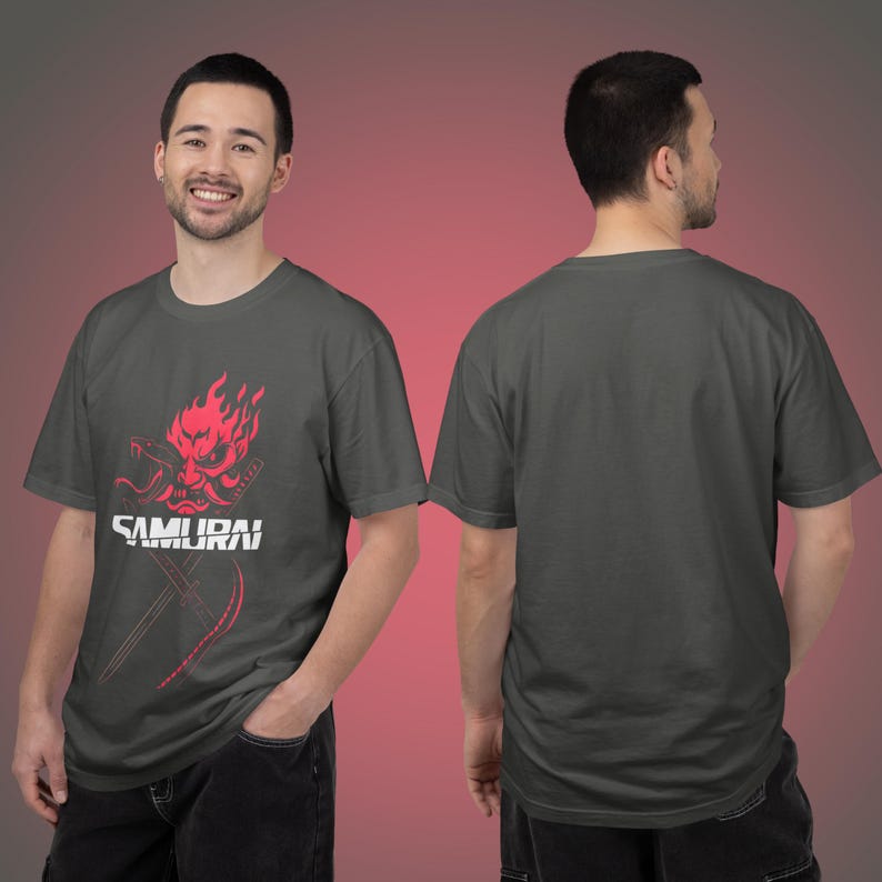 May include: Dark gray t-shirt featuring a red samurai graphic with the word "SAMURAI" in white. The design includes a flaming mask and crossed swords. The shirt is a crew neck style.