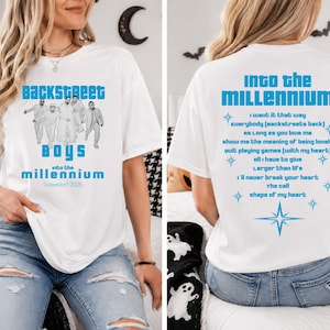 Könnte beinhalten: Ein weißes Kurzarm-T-Shirt mit einer blauen Grafik der Backstreet Boys auf der Vorderseite und dem Text "Backstreet Boys into the Millennium Düsseldorf 2026". Die Rückseite zeigt eine Liste von Songtiteln in blauem Text mit Sternsymbolen.