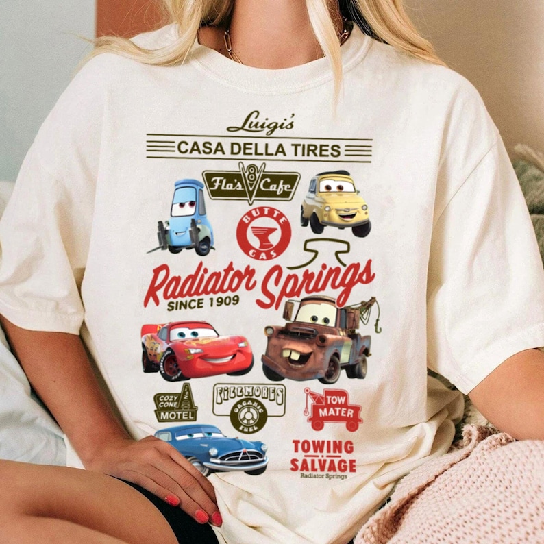 Pu&ograve; includere: Una t-shirt color bianco sporco con una stampa grafica dei personaggi e dei loghi del film Cars. Il design include Luigi, Guido, Lightning McQueen, Mater e Fillmore, con il testo Luigi's Casa Della Tires, Radiator Springs e Tow Mater.