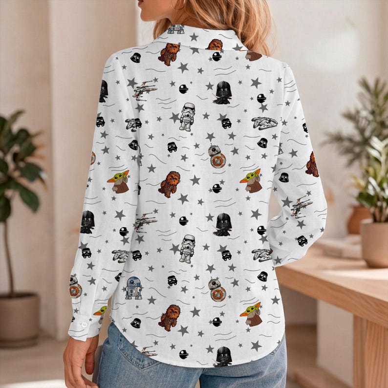 May include: White button-down shirt with a Star Wars pattern. The long-sleeved shirt features characters and symbols from the franchise, including Darth Vader, Baby Yoda, and Stormtroopers, along with stars and spaceships.