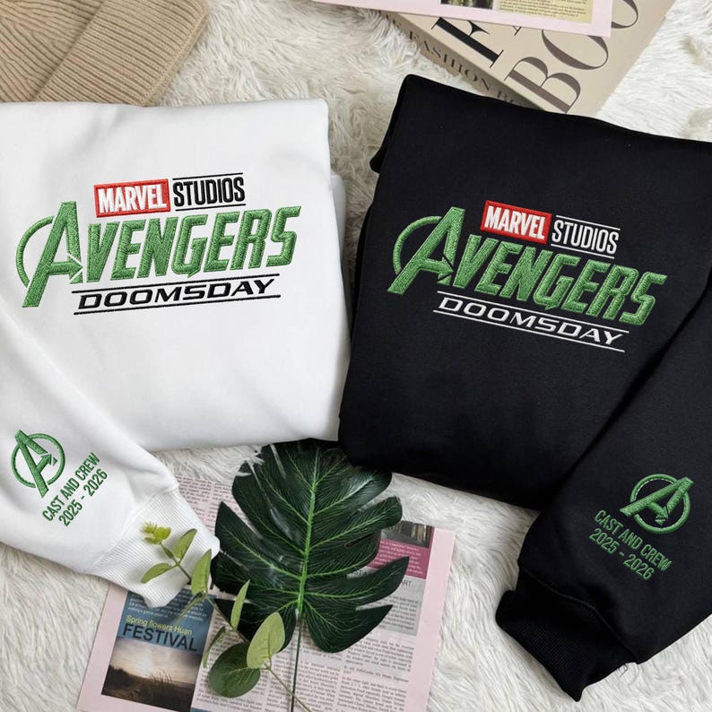 May include: White and black sweatshirts featuring the Marvel Studios Avengers logo in green embroidery. The text "DOOMSDAY" is below the logo. The white sweatshirt has the text "CAST AND CREW 2025-2026" on the sleeve.