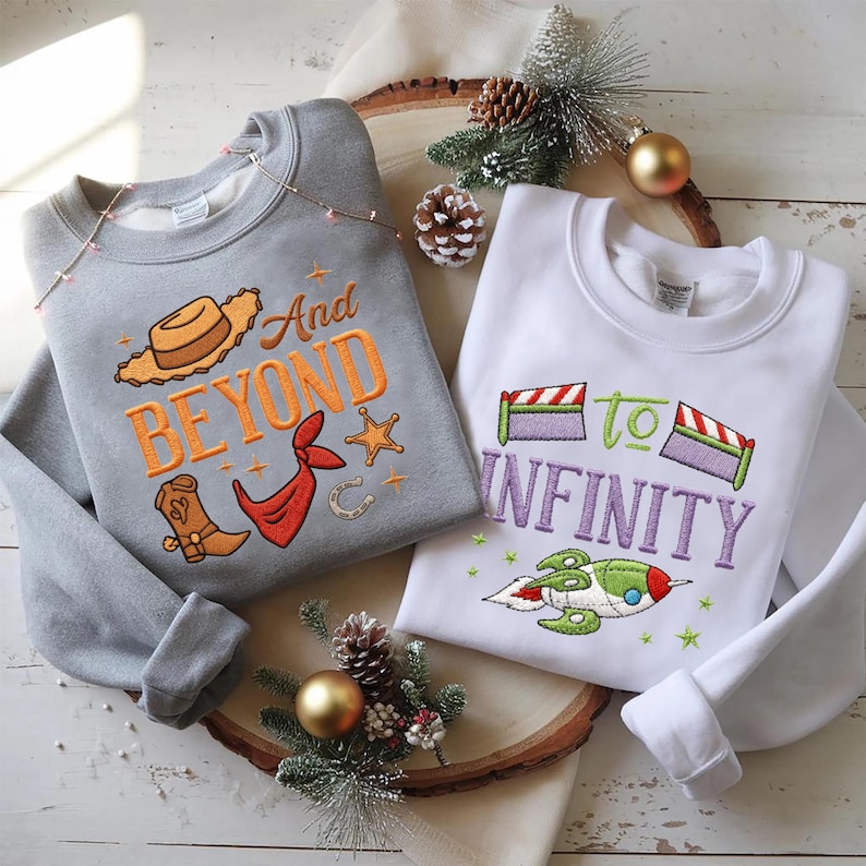 Puede incluir: Dos sudaderas con dise&ntilde;os bordados. Una es gris con "And Beyond" y gr&aacute;ficos tem&aacute;ticos de vaqueros. La otra es blanca con "To Infinity" y un dise&ntilde;o de cohete. Ambas son de cuello redondo.