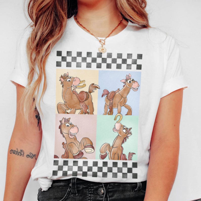 May include: White t-shirt featuring a cartoon horse design in four panels. The horse is brown with a saddle and a smiling expression. The design is framed by a black and white checkered pattern.