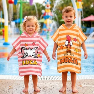 May include: Two children wearing hooded beach towels. One towel is pink and white striped with a cartoon pig graphic and the name "LUCA". The other is orange and white striped with a cartoon rooster graphic and the name "NOAH".