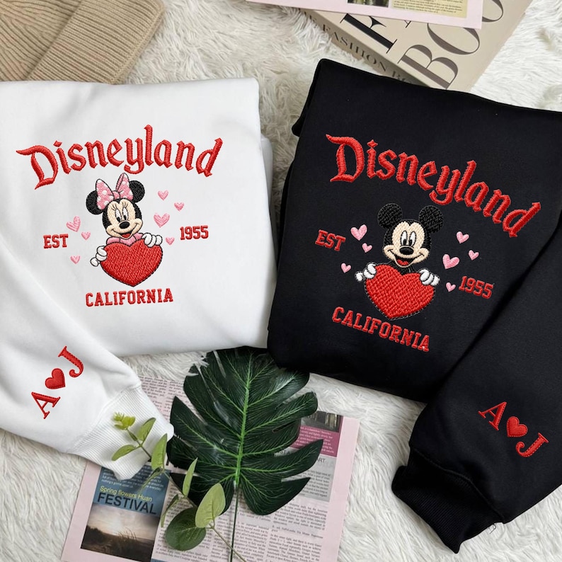 Puede incluir: Sudaderas blancas y negras con bordado "Disneyland", Mickey y Minnie Mouse, y un coraz&oacute;n. Las sudaderas tambi&eacute;n presentan el texto "EST 1955 CALIFORNIA" e iniciales en las mangas.