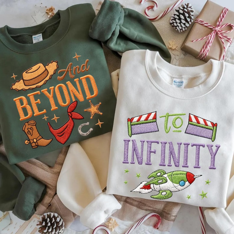 Puede incluir: Dos sudaderas de cuello redondo. Una es verde oliva con bordados de tem&aacute;tica vaquera y la frase "And Beyond". La otra es de color blanco roto con "to INFINITY" y un dise&ntilde;o de cohete. La decoraci&oacute;n festiva navide&ntilde;a rodea las camisas.