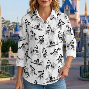 May include: White button-down shirt with a repeating black and gray Mickey Mouse pattern. The design features Mickey Mouse at the helm of a ship and steering a ship's wheel. The shirt has long sleeves and a classic collar.