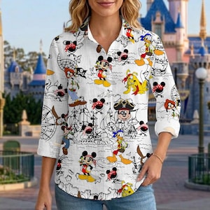 May include: White button-down shirt featuring a pirate-themed design with cartoon characters. The long-sleeved shirt has a repeating pattern of Mickey Mouse, Donald Duck, and other characters in pirate attire, with ships and treasure maps.