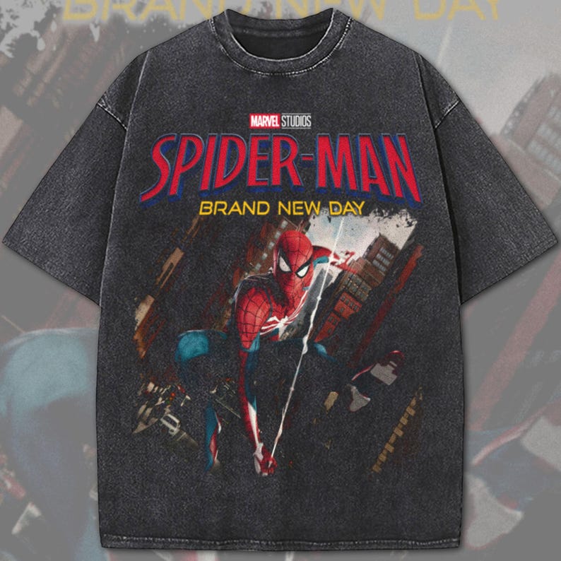 May include: A dark gray t-shirt featuring the Marvel Studios Spider-Man logo and a graphic of Spider-Man in action. The text "BRAND NEW DAY" is below the logo. The shirt has a vintage, distressed look.