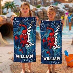 May include: Two rectangular blue beach towels featuring the superhero Spider-Man in red and blue, with the name "WILLIAM" in white. The towels have a web design background and the word "YEAH" in white. The towels are held by two young girls.
