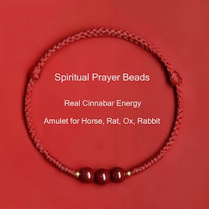 Könnte beinhalten: Rotes spirituelles Gebetsarmband mit drei Zinnoberperlen und goldenen Akzenten. Der Text auf dem Bild lautet: Spiritual Prayer Beads, Real Cinnabar Energy, Amulet for Horse, Rat, Ox, Rabbit.