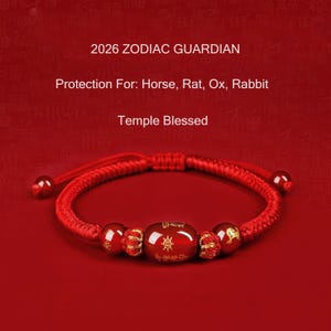 Könnte beinhalten: Rotes geflochtenes Armband mit drei runden Perlen und einer ovalen Mittelperle. Die Mittelperle hat goldfarbene Symbole. Der Text auf dem Bild lautet "2026 ZODIAC GUARDIAN" und "Protection For: Horse, Rat, Ox, Rabbit".