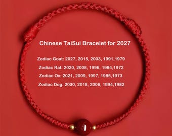 May include: A red braided cord bracelet featuring a single dark red bead with gold accents. The text reads: Chinese TaiSui Bracelet for 2027, Zodiac Goat: 2027, 2015, 2003, 1991, 1979, Zodiac Rat: 2020, 2008, 1996, 1984, 1972, Zodiac Ox: 2021, 2009, 1997, 1985, 1973, Zodiac Dog: 2030, 2018, 2006, 1994, 1982.