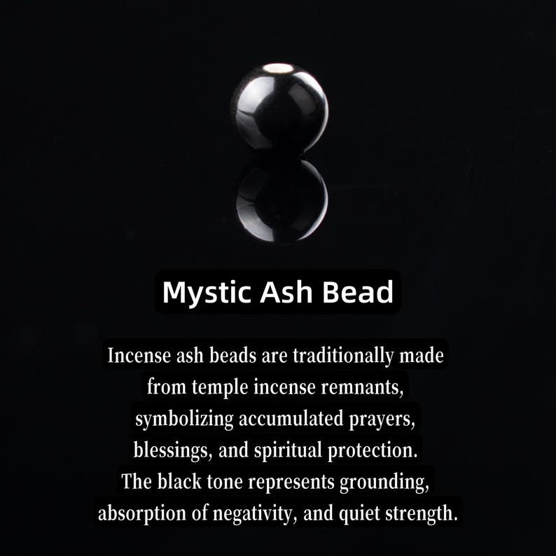May include: A glossy, black Mystic Ash Bead, reflecting on a dark surface. The image includes text describing the bead's symbolism: grounding, protection, and strength. The bead is made from temple incense remnants.