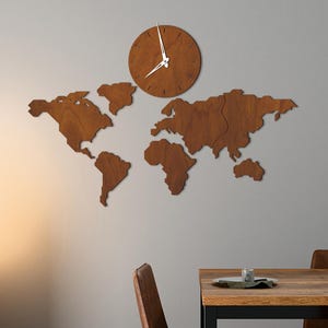 May include: A wooden world map and a round clock are mounted on a gray wall. The clock has white hands and a brown face. The map is made of individual wooden continents. The color of the wood is beech.