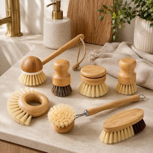 Könnte beinhalten: Ein Set aus sieben Reinigungsbürsten aus Bambus in verschiedenen Formen und Größen. Das Set enthält runde Handbürsten, eine Spülbürste mit langem Stiel und Aufhängeschlaufe, eine ringförmige Bürste sowie eine ovale Schrubbbürste mit hellen und dunklen Borsten.