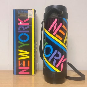 May include: A black thermal carafe with a black strap. The carafe has a colorful design with the words "NEW YORK" in a rainbow pattern.