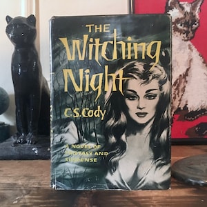 May include: A vintage paperback book titled "The Witching Night" by C.S. Cody. The cover features a woman with long dark hair and a mysterious expression. The book is a novel of fantasy and suspense.