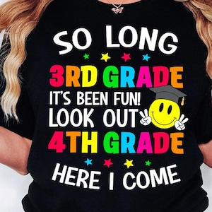 May include: Black t-shirt with the text "So Long 3rd Grade It's Been Fun! Look Out 4th Grade Here I Come" in rainbow colors. A smiling yellow face with a graduation cap is in the center of the text.