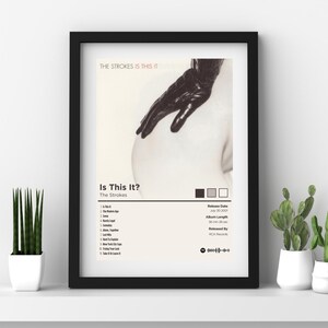 以下が含まれることがあります： ストロークスの「Is This It?」の白黒のアルバムカバー。カバーには、黒い手袋をした手が裸の胴体に向かって伸びている。アルバムのタイトルとアーティスト名は、白い背景に黒い文字で印刷されている。トラックリストとアルバムの詳細が、白い背景に黒い文字で印刷されている。