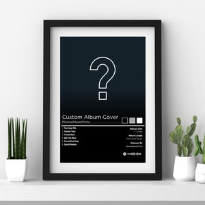 Op de afbeelding: Een ingelijste, op maat gemaakte albumcoverprint met een zwart frame. Het kunstwerk toont een groot wit vraagteken op een donkerblauwe tot zwarte gradiënt achtergrond. Onder het kunstwerk staat de tekst "Custom Album Cover" en andere details.