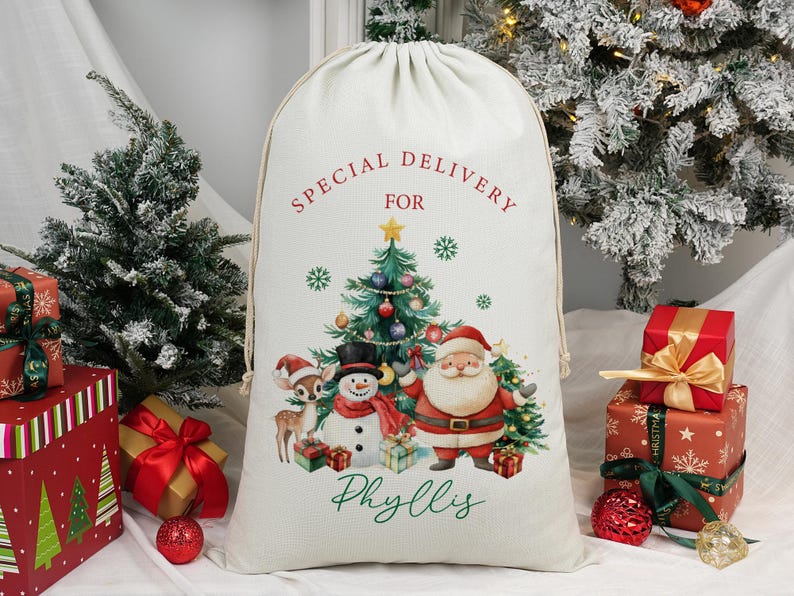 May include: A cream Christmas sack with a drawstring. It features a festive illustration of Santa Claus, a snowman, and a reindeer, with a Christmas tree. The text "SPECIAL DELIVERY FOR Phyllis" is printed on the sack.
