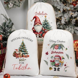 May include: White Christmas gift bags with drawstring closures. The bags feature festive illustrations of Santa Claus, Christmas trees, and gnomes. Text includes "Special Delivery for Tabitha", "Merry Christmas Johnson", and a name.