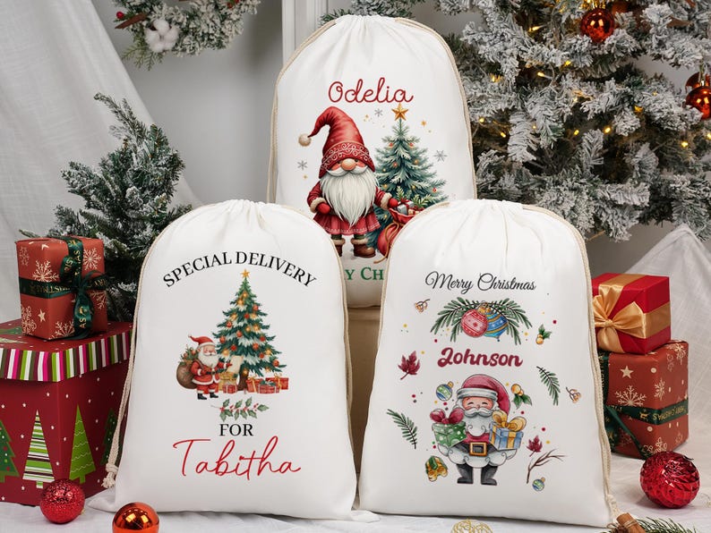 May include: White Christmas gift bags with drawstring closures. The bags feature festive illustrations of Santa Claus, Christmas trees, and gnomes. Text includes "Special Delivery for Tabitha", "Merry Christmas Johnson", and a name.
