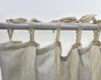 Peut inclure: Quatre rideaux de couleur crème avec un tissu tissé texturé sont suspendus à une tringle en bois blanc. Chaque rideau est surmonté d'un lien en crochet blanc.
