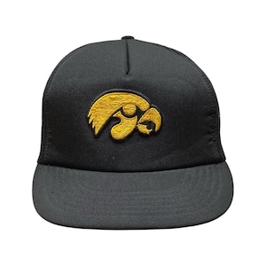 Puede incluir: Gorra de camionero negra con el logotipo dorado bordado de los Iowa Hawkeyes. La gorra tiene una visera curva y una parte trasera de malla. Un accesorio clásico y elegante para los fans.