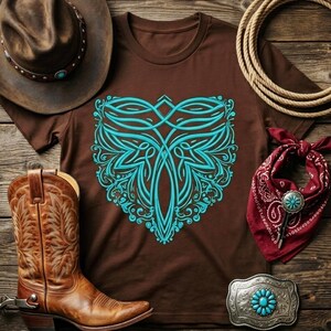 May include: A brown t-shirt with a turquoise ornamental design, cowboy boots, a brown cowboy hat, a red bandana, a silver belt buckle with turquoise accents, and a rope on a wooden surface. Western-themed apparel.