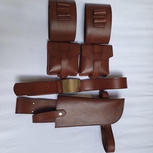 Puede incluir: Un cintur&oacute;n utilitario de cuero marr&oacute;n con m&uacute;ltiples bolsillos y una funda. El cintur&oacute;n presenta una hebilla dorada y est&aacute; dise&ntilde;ado para guardar varios objetos. El cuero parece ser de alta calidad, con un acabado liso.