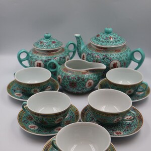 Puede incluir: Juego de t&eacute; turquesa con un patr&oacute;n floral y geom&eacute;trico. El juego incluye dos teteras, una lechera, seis tazas y platillos. El juego de t&eacute; tiene un dise&ntilde;o asi&aacute;tico tradicional con detalles en rojo y dorado.