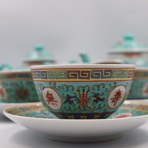 Puede incluir: Juego de t&eacute; de porcelana con dise&ntilde;o turquesa y dorado. El juego incluye tazas, platillos y una tetera. Las tazas y los platillos tienen una base blanca con un borde con dibujos turquesa y dorado.
