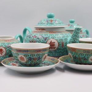 Puede incluir: Un juego de t&eacute; turquesa completo con tetera, crema, tazas y platillos. El juego presenta un estampado floral con caracteres chinos rojos. La tetera tiene forma redondeada con tapa y asa. Las tazas y platillos son peque&ntilde;os y delicados.