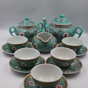 Puede incluir: Un juego de t&eacute; turquesa completo con un dise&ntilde;o floral y geom&eacute;trico. El juego incluye una tetera, azucarero, lechera y seis tazas de t&eacute; con platillos. Cada pieza presenta un interior blanco y ribete dorado.
