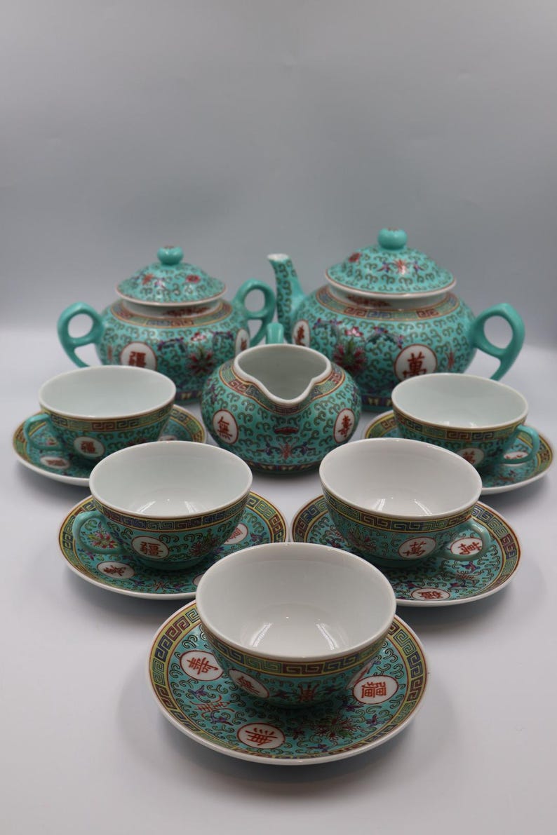 Puede incluir: Un juego de t&eacute; turquesa completo con un dise&ntilde;o floral y geom&eacute;trico. El juego incluye una tetera, azucarero, lechera y seis tazas de t&eacute; con platillos. Cada pieza presenta un interior blanco y ribete dorado.