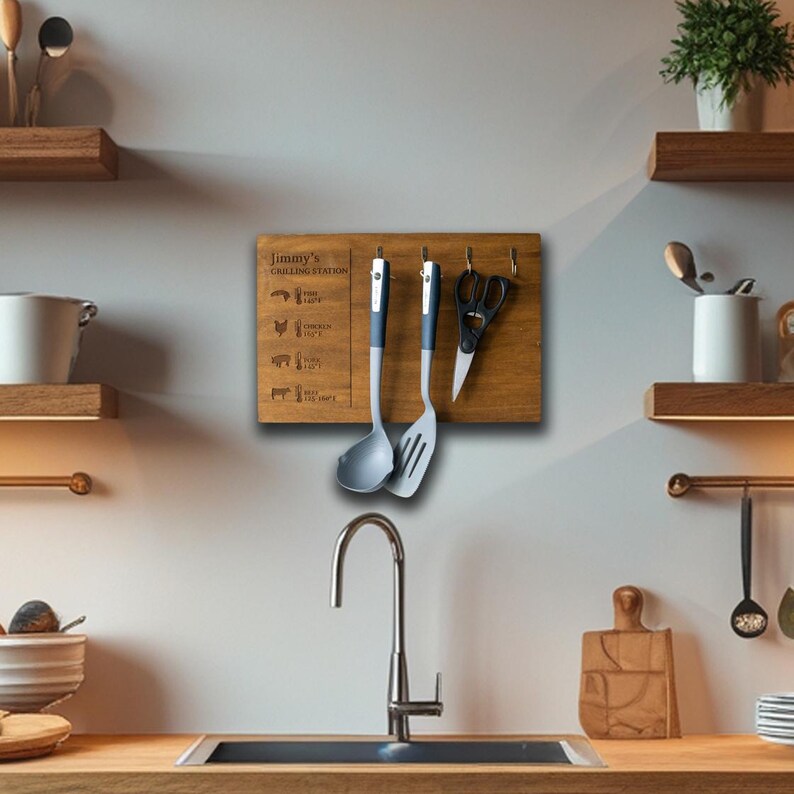May include: A wooden grilling station with hooks for hanging utensils. The station has a brown wood finish and is labeled "Jimmy's Grilling Station". It features a list of different types of meat and their corresponding cooking times. Two gray and black kitchen utensils are hanging from the hooks.