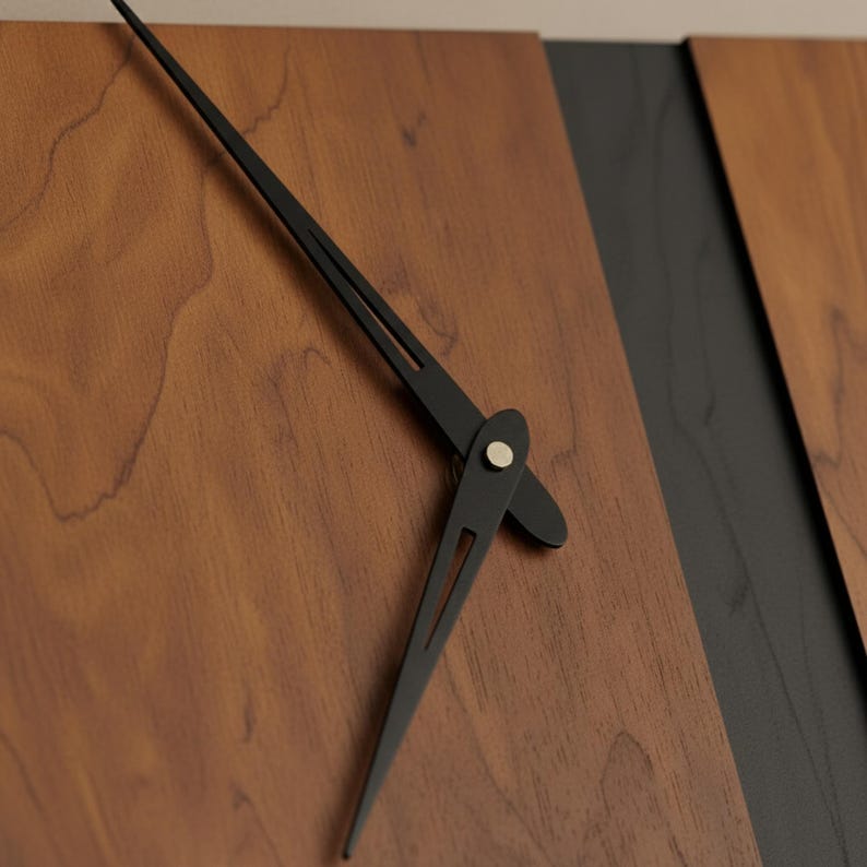 May include: Close-up of a modern wall clock. The clock features a wooden face with a dark brown finish and black clock hands. The hands are thin and sleek, with a minimalist design. The clock's face is divided by a black stripe.