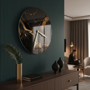 Puede incluir: Un reloj de pared circular con un patrón de mármol negro y dorado en su esfera. El reloj tiene dos manecillas doradas puntiagudas centradas en el dial. El diseño es elegante y pulido, montado sobre una pared de color verde azulado estriada.