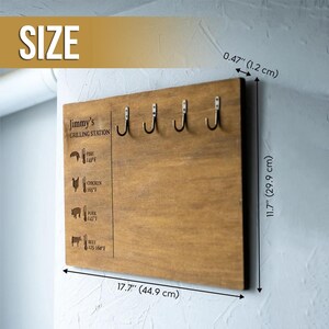 May include: A wooden grilling station sign with five hooks, measuring 17.7 inches by 11.7 inches. The sign features the text "Jimmy's Grilling Station" and a chart with recommended cooking temperatures for fish, chicken, pork, and beef.