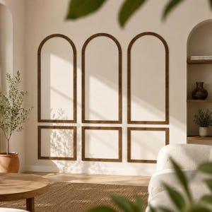 May include: Three wall-mounted decorative wooden frames featuring an arched top section and a rectangular bottom section. The frames are dark brown and are mounted on a plain, light-coloured wall, creating a symmetrical architectural wall paneling design.