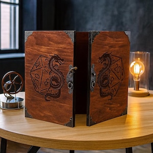 Może przedstawiać: Drewniane pudełko do gier planszowych w kolorze ciemnobrązowym. Pudełko posiada wzór smoka i dwudziestościennej kostki. Posiada metalowe wzmocnienia narożników i metalową zatrzask. Pudełko jest otwarte, ukazując wnętrze.