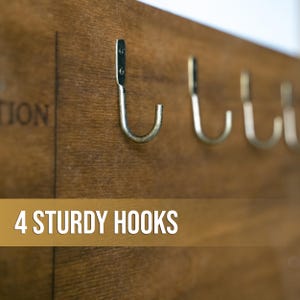 May include: A wooden wall-mounted key holder with four sturdy metal hooks. The key holder has the text "4 STURDY HOOKS" printed on it.