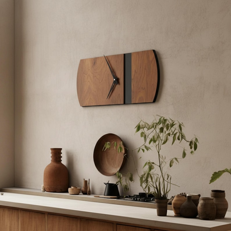 Horizontal oblong wall clock in walnut-style wood mounted on a light textured wall, featuring a modern rectangular curved-edge shape, black accent strip, and black clock hands. Contemporary wood wall clock shown above a kitchen counter with decor, ideal as a large wall clock, minimalist clock, silent wall clock, and mid century clock for living room, kitchen, or dining space.