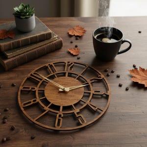 Puede incluir: Un reloj de pared de madera con acabado marr&oacute;n oscuro. El reloj presenta un dise&ntilde;o circular con n&uacute;meros romanos y manecillas doradas. Una taza de caf&eacute;, libros y hojas de oto&ntilde;o tambi&eacute;n est&aacute;n sobre la superficie de madera.